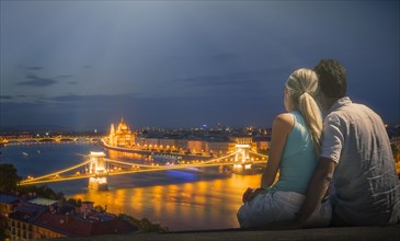 Caucasian couple admiring scenic view of bridge at night