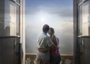 Caucasian couple admiring scenic view of lake from balcony