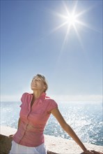 Caucasian woman basking in sunshine near ocean