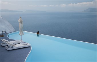Caucasian woman in infinity pool admiring scenic view of ocean
