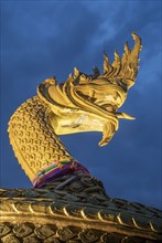 Ornate golden snake statue under cloudy sky