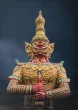 Ornate demon statue under cloudy sky