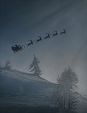 Silhouette of Santa and reindeer flying sleigh in winter