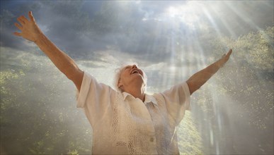 Smiling Caucasian woman looking up at sunbeams