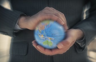 Caucasian businessman holding defocused globe in hands