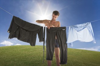 Caucasian businessman hanging suit on clothesline on hill