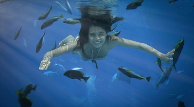 Asian woman swimming underwater with fish