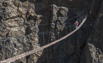 Caucasian man crossing rope bridge on mountain