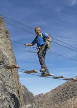 Caucasian man crossing rope bridge on mountain