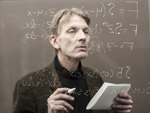 Caucasian teacher looking at formula on glass wall