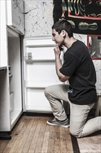 Mixed race man looking in refrigerator