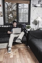 Mixed race man sitting on sofa with laptop