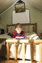 Caucasian boy laying in bed in tent