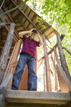 Caucasian boy using binoculars in tree house