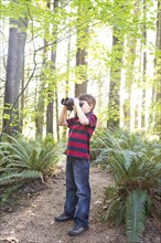 Caucasian boy using binoculars in forest