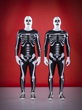 Caucasian men wearing skeleton costumes