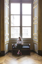 Caucasian teenage girl studying in ornate window at Louvre Museum