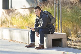 Mixed race college student using digital tablet on campus