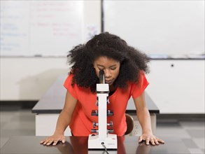 Black girl using microscope in chemistry lab