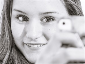 Caucasian teenage girl taking picture with cell phone