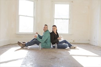Mixed race couple sitting on floor of new home