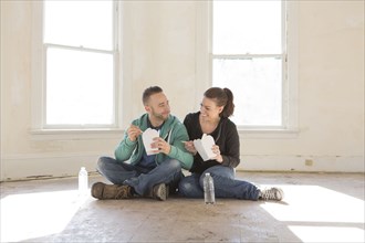 Mixed race couple eating takeout on floor of new home