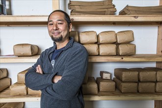 Mixed Race man posing near shelves of coffee bags