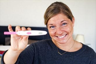 Caucasian woman holding positive pregnancy test