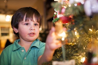 Caucasian boy decorating Christmas tree