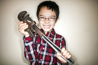 Mixed race boy playing with metal wrench