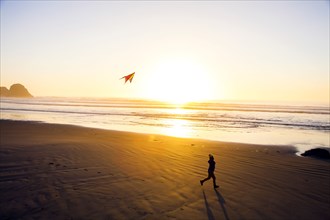 Caucasian woman flying kite on beach