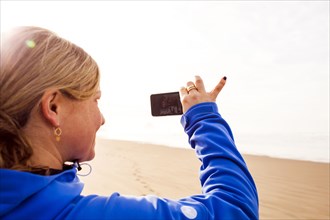 Caucasian woman taking pictures on beach