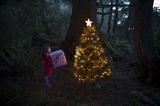 Caucasian girl by Christmas tree in forest
