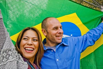 Hispanic couple holding Brazilian flag