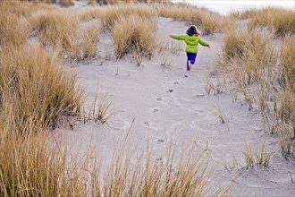 Caucasian girl running on sand dunes