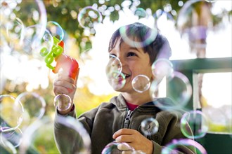 Mixed race boy playing with bubbles outdoors