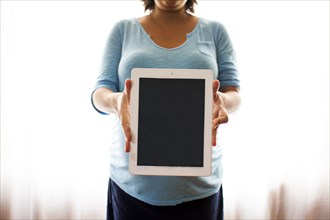 Pregnant Hispanic woman holding tablet computer