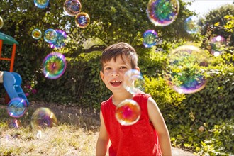 Mixed race boy playing with bubbles in backyard