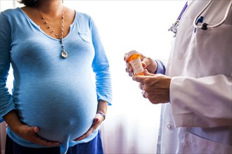 Doctor giving pregnant woman prescription medicine