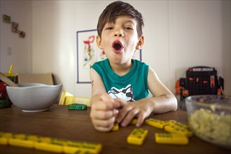 Mixed race boy playing with dominoes at kitchen table