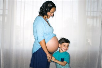 Boy listening to mother's pregnant belly