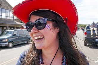Caucasian woman wearing cowboy hat and face paint in street
