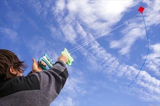 Low angle view of Caucasian man flying kite in blue sky