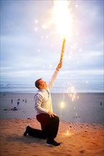 Caucasian man holding fireworks on beach