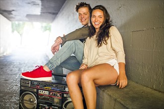Caucasian couple listening to boom box in tunnel