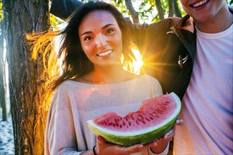 Caucasian couple eating watermelon at sunset