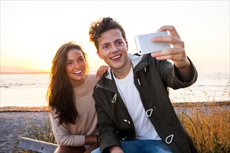 Caucasian couple taking selfie on beach