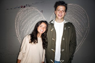 Caucasian couple smiling near chalk heart on wall