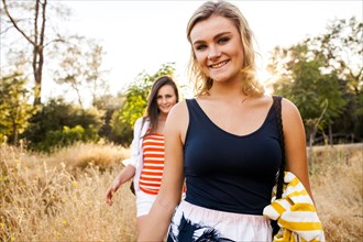 Caucasian teenage girls walking in tall grass in field