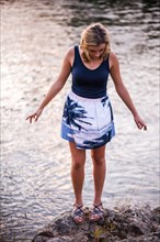 Caucasian teenage girl standing on rocky riverbank